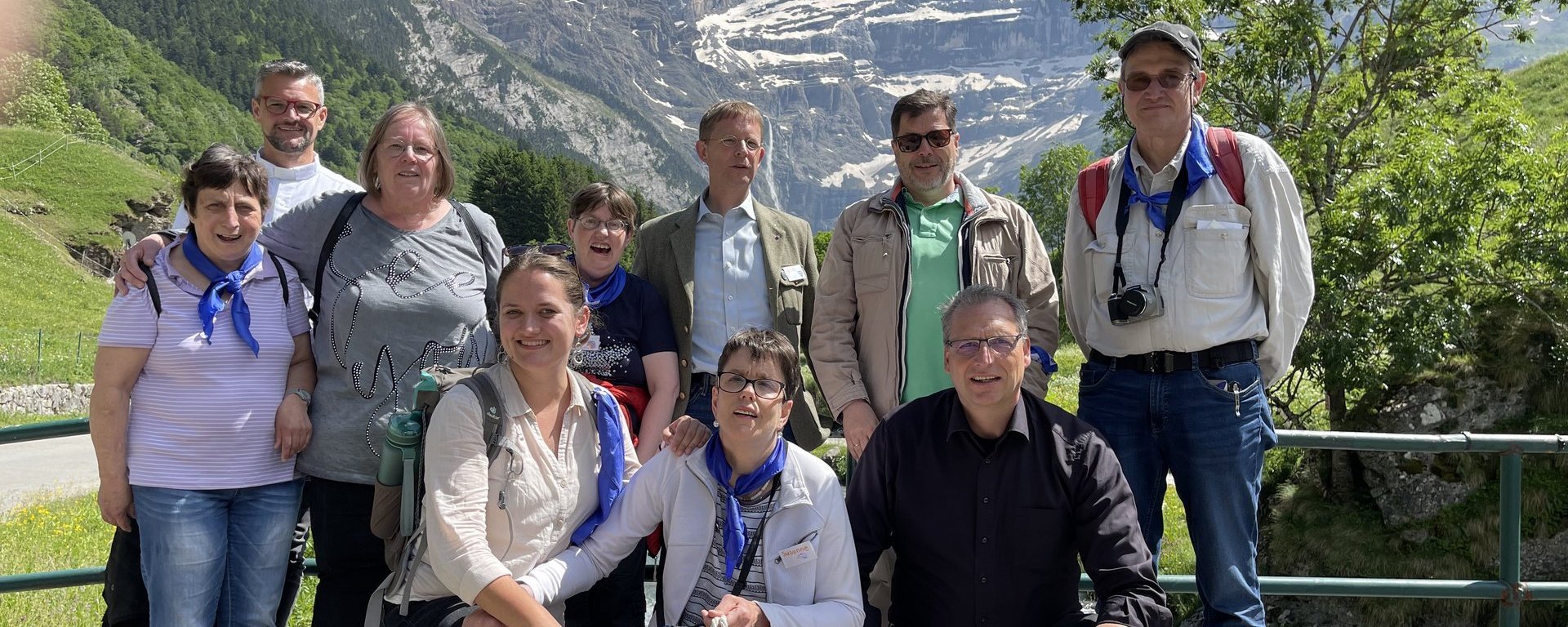 Gruppenfoto: Frauen und Männer auf einer Brücke - im Hintergrund Alpenpanorama