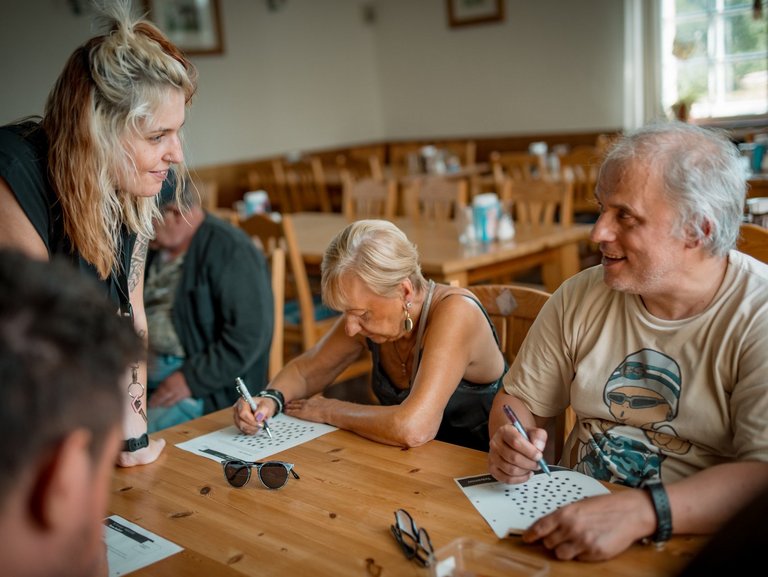 Eine freundliche Mitarbeiterin mit Brille und dunklen Haaren ist im Gespräch mit einem jungen Mann